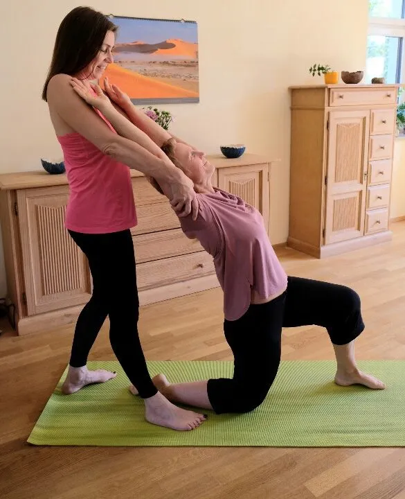 Hilfestellung bei einer Yogaübung auf der Matte